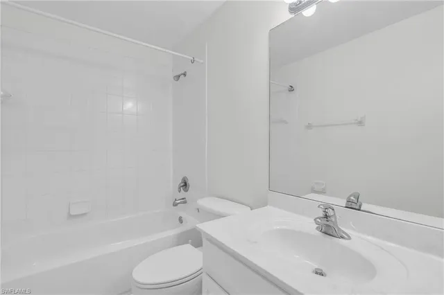 a bathroom with a bathtub shower sink vanity mirror and toilet
