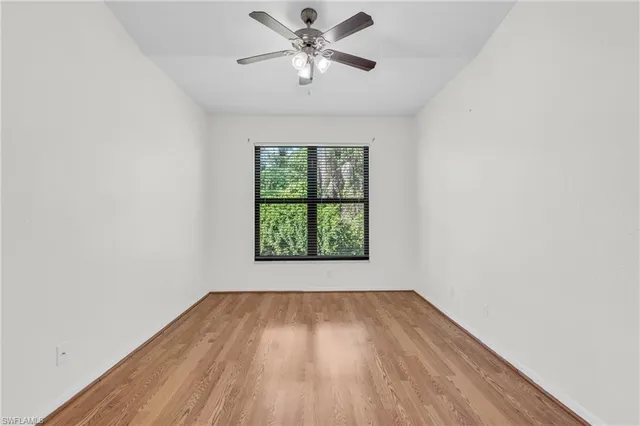 an empty room with a window and a ceiling fan
