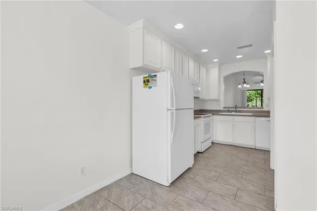 a kitchen with white cabinets and white appliances