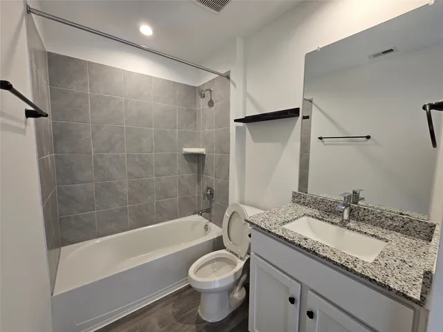 a bathroom with a granite countertop sink a toilet and shower