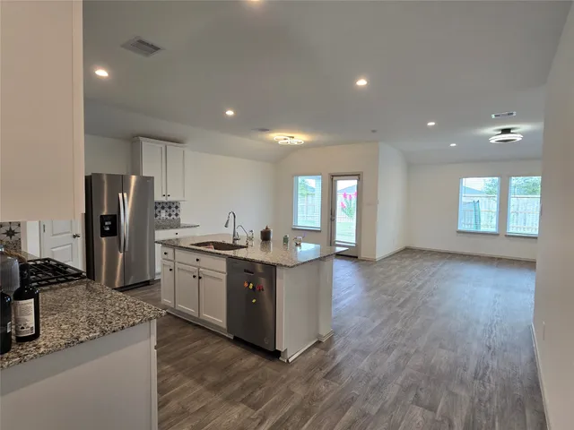 a large kitchen with kitchen island a stove a refrigerator a sink a microwave and island in the center