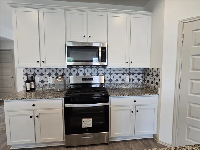 a kitchen with kitchen island granite countertop a sink stove and refrigerator