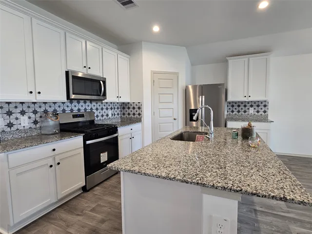 a kitchen with granite countertop a stove a sink and a microwave
