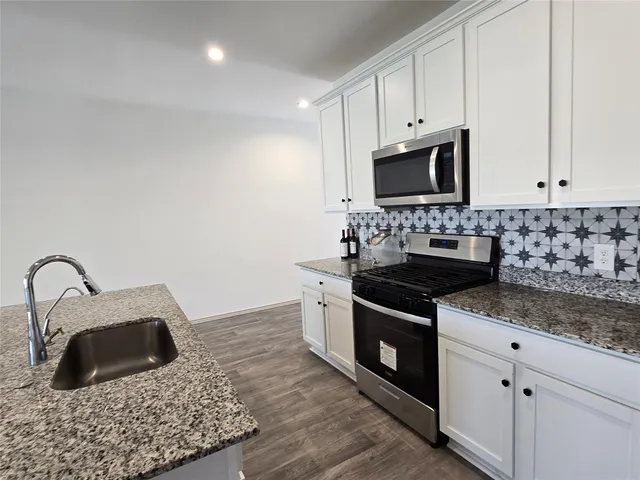 a kitchen with white cabinets and appliances