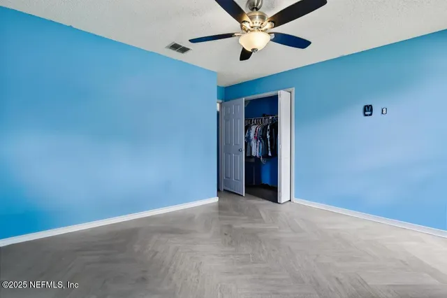 an empty room with closet and a chandelier fan