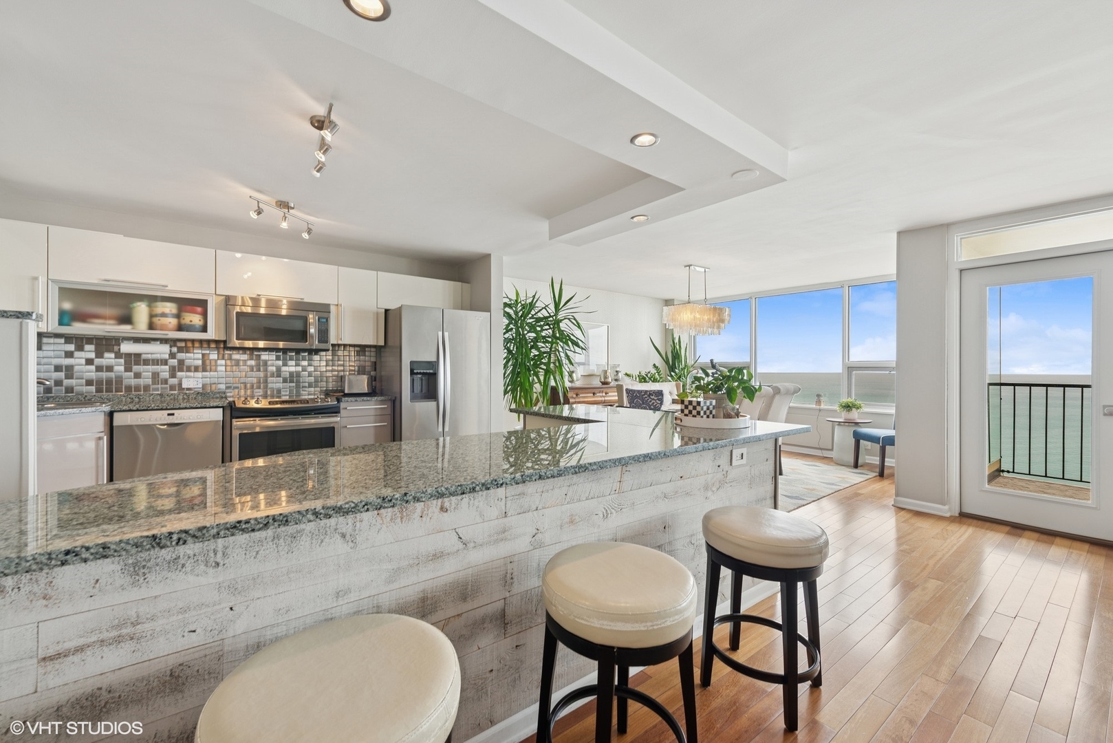 5733 North Sheridan Road, Unit 29D Chicago, IL 60660 - Photo 11 of 40 a kitchen with stainless steel appliances granite countertop a stove a sink a dining table and chairs with wooden floor