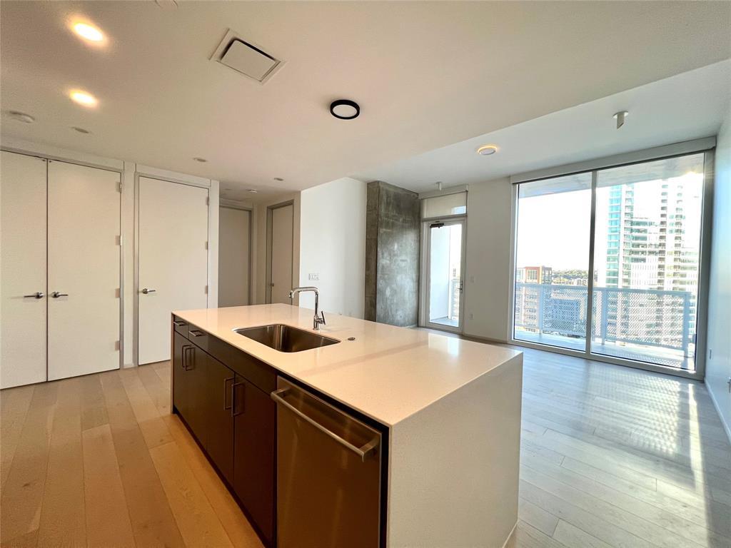 301 West Avenue, Unit 1502 Austin, TX 78701 - Photo 3 of 26 Kitchen with expansive windows, modern cabinets, light wood finished floors, dishwasher, and a kitchen island with sink