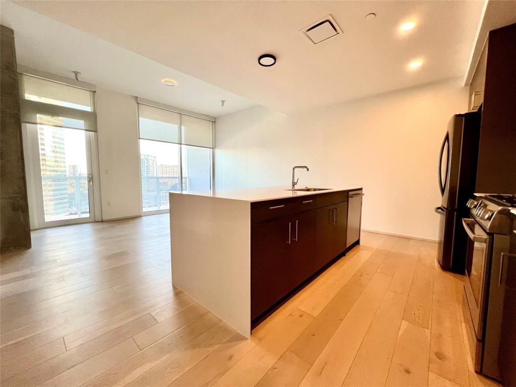 301 West Avenue, Unit 1502 Austin, TX 78701 - Photo 4 of 26 Kitchen with modern cabinets, stainless steel appliances, dark brown cabinets, light wood finished floors, and expansive windows
