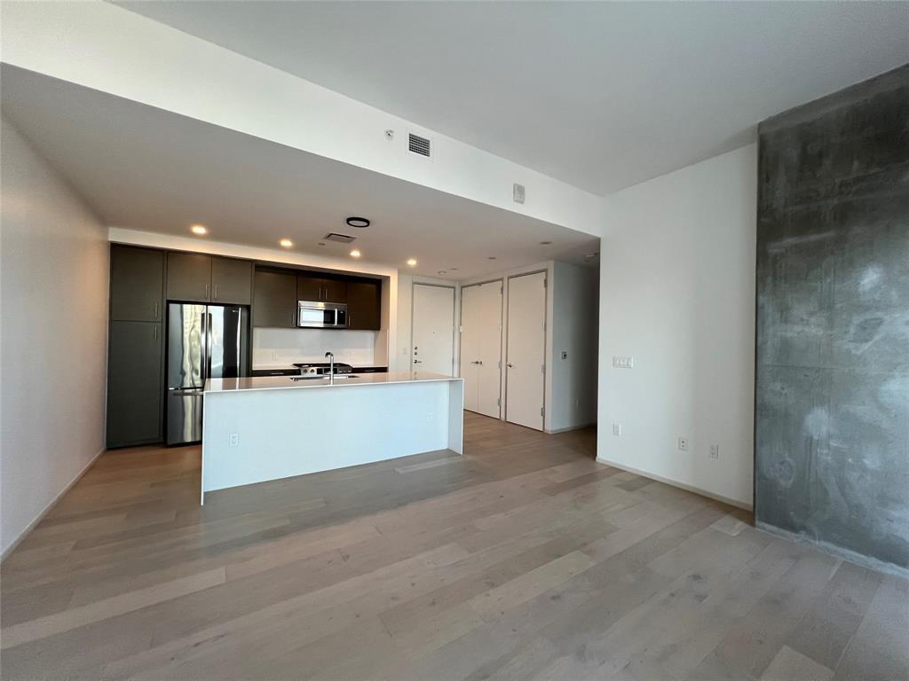 301 West Avenue, Unit 1502 Austin, TX 78701 - Photo 7 of 26 Kitchen with an island with sink, light wood-style flooring, stainless steel appliances, light countertops, and dark brown cabinets