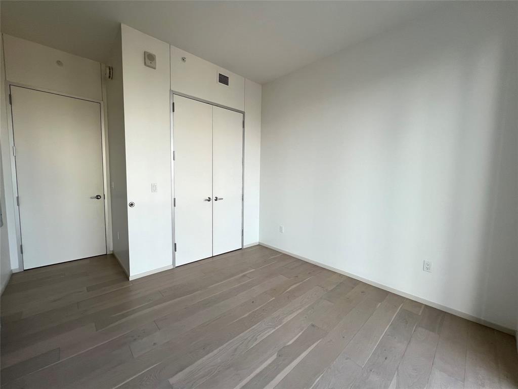 301 West Avenue, Unit 1502 Austin, TX 78701 - Photo 9 of 26 Unfurnished bedroom featuring hardwood / wood-style flooring and a closet