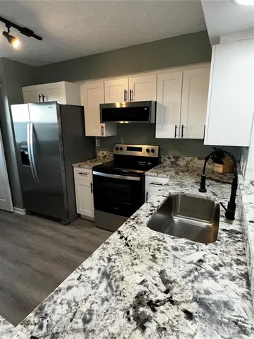 a kitchen with granite countertop a refrigerator sink and wooden cabinets