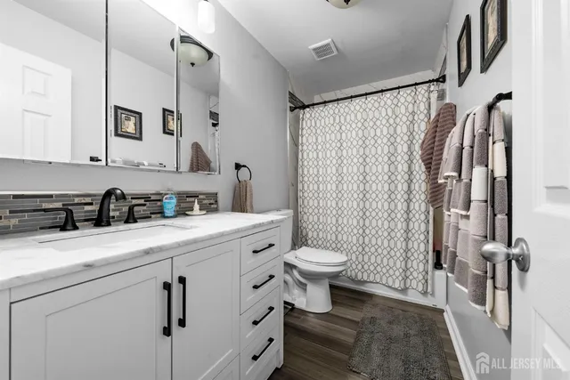 a bathroom with a sink a toilet a mirror and shower