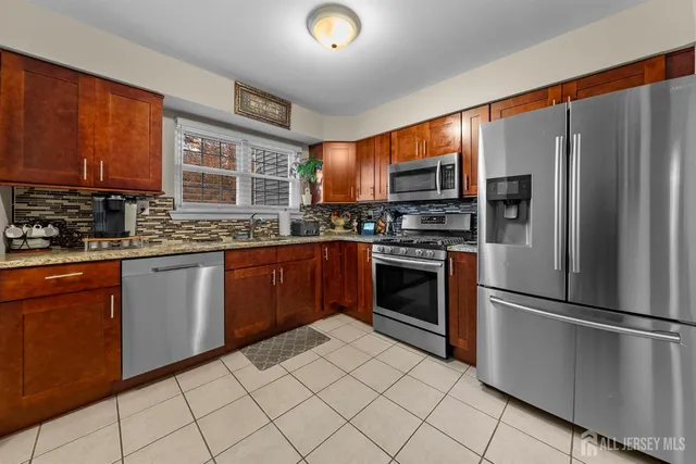 a kitchen with stainless steel appliances granite countertop a stove top oven a sink and a refrigerator