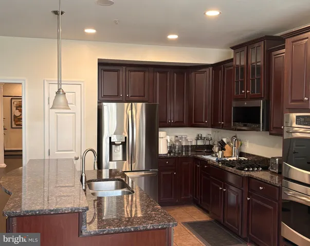a kitchen with stainless steel appliances granite countertop a refrigerator a sink and wooden cabinets