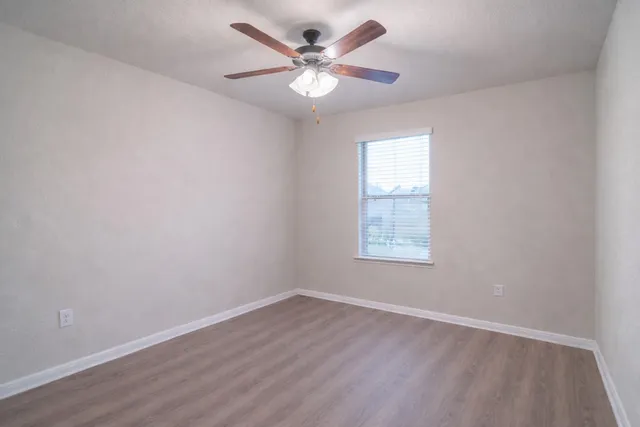 an empty room with wooden floor and ceiling fan