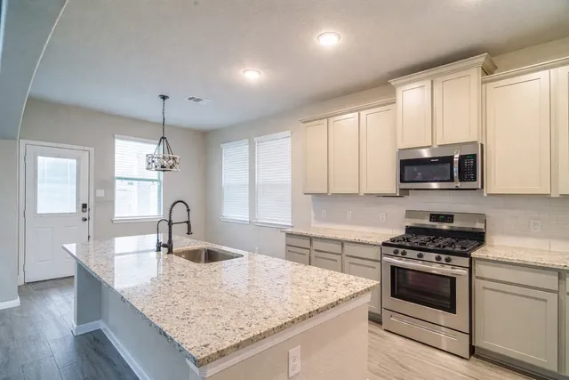 a kitchen with granite countertop a sink stainless steel appliances and cabinets