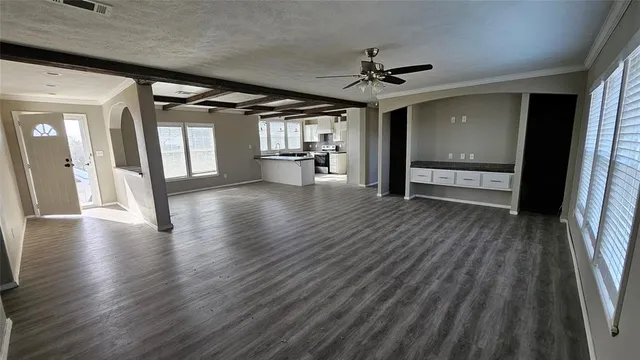 a view of an empty room with wooden floor a ceiling fan and windows