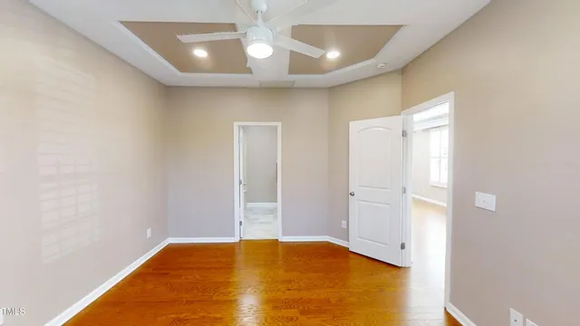 an empty room with wooden floor fan and windows
