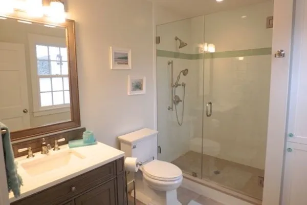 a bathroom with a toilet a sink a mirror and a shower