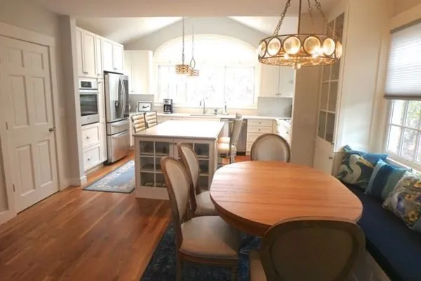 a dining room with wooden floor a chandelier a wooden table and chairs