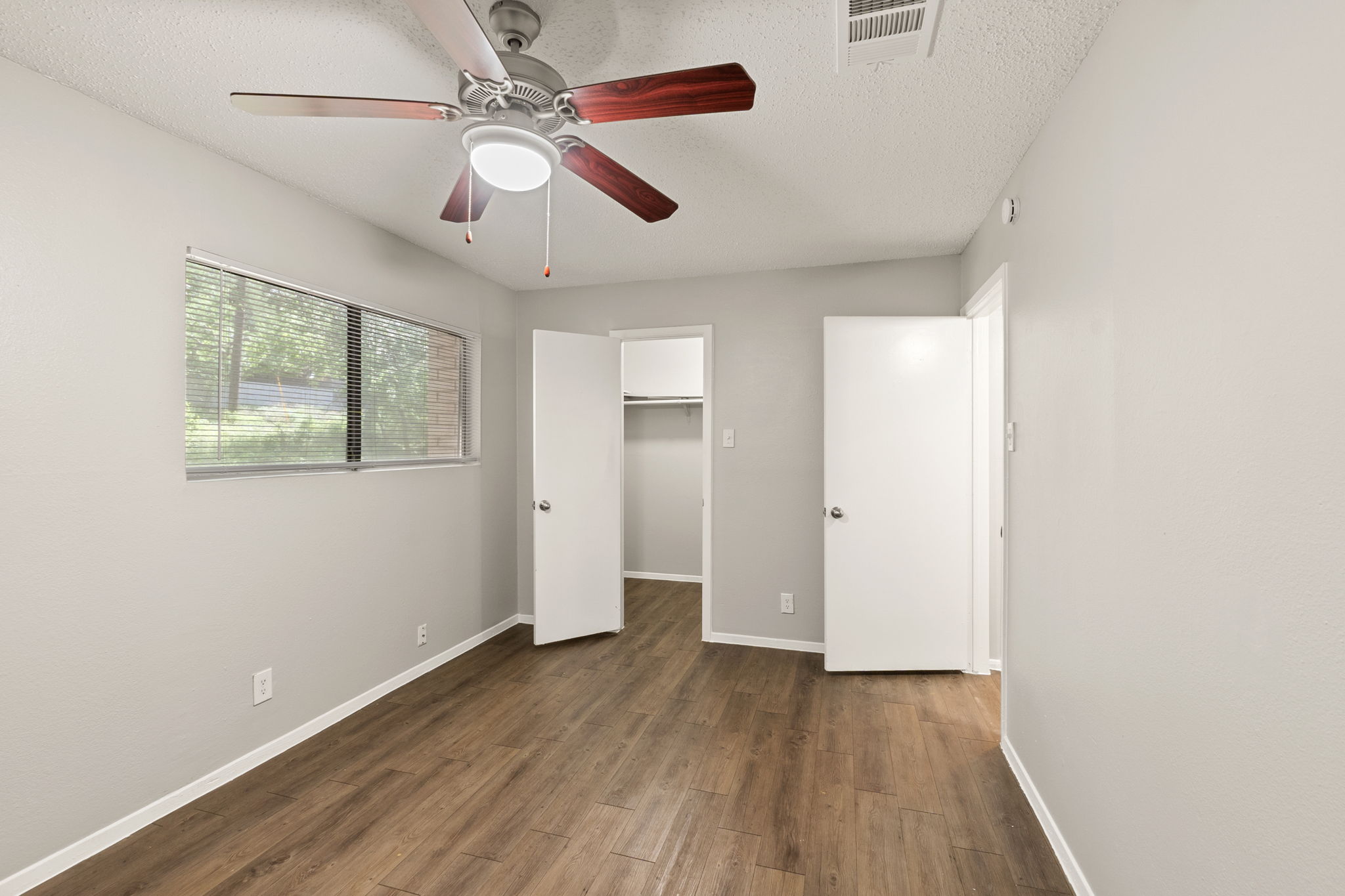 2001 South Interstate 35 Frontage Road, Unit 229 Austin, TX 78741 - Photo 16 of 24 Unfurnished bedroom with a walk in closet, a textured ceiling, dark wood-type flooring, and a ceiling fan
