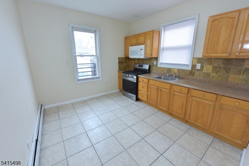 117 Scheerer Avenue Newark, NJ 07112 - Photo 11 of 19 a large kitchen with a sink window and cabinets