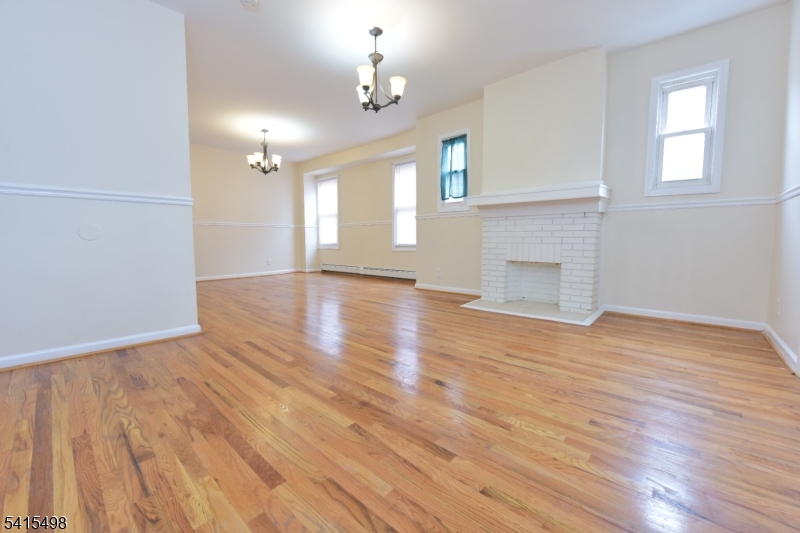 117 Scheerer Avenue Newark, NJ 07112 - Photo 15 of 19 an empty room with wooden floor fireplace and windows
