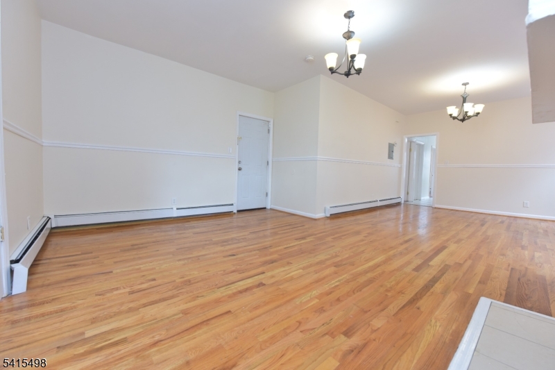 117 Scheerer Avenue Newark, NJ 07112 - Photo 16 of 19 an empty room with wooden floor chandelier fan and windows