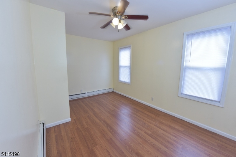 117 Scheerer Avenue Newark, NJ 07112 - Photo 6 of 19 an empty room with wooden floor ceiling fan and windows