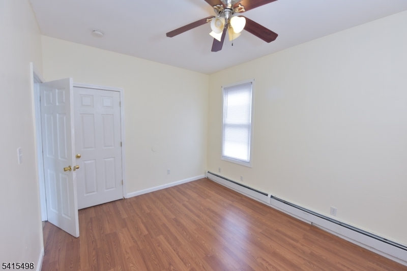 117 Scheerer Avenue Newark, NJ 07112 - Photo 10 of 19 an empty room with wooden floor chandelier fan and windows