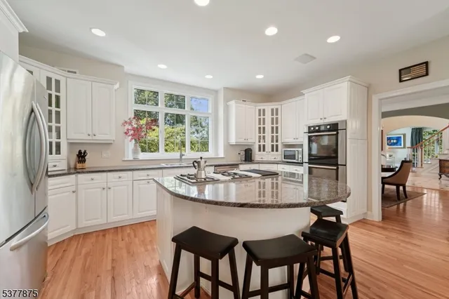 a kitchen with stainless steel appliances granite countertop a table chairs sink refrigerator and cabinets