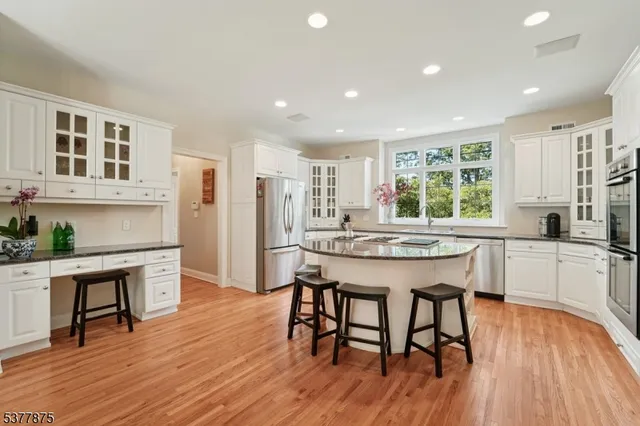 a kitchen with stainless steel appliances granite countertop a kitchen island hardwood floor sink stove dining table and chairs