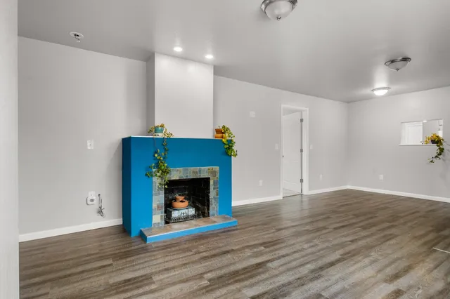 a view of an empty room with wooden floor and a fireplace