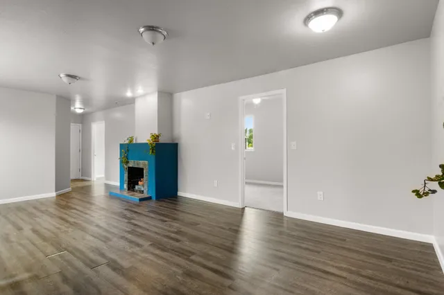 an empty room with wooden floor and a fireplace