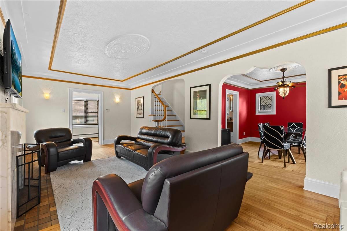 Living area featuring decorative ceiling molding, a built-in fireplace, and wood-finish flooring