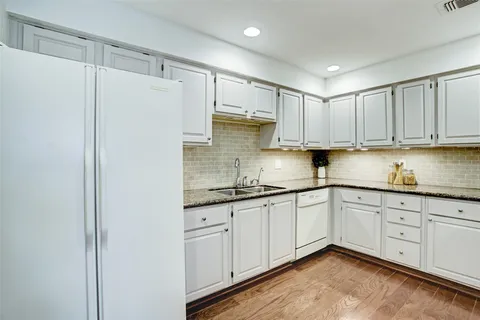 a kitchen with granite countertop white cabinets and white appliances