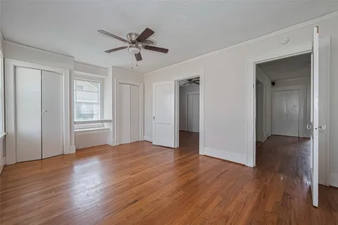 a view of empty room with wooden floor and ceiling fan