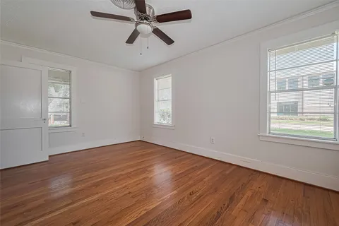 a view of empty room with wooden floor and fan