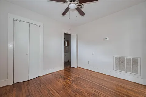a view of empty room with wooden floor and ceiling fan