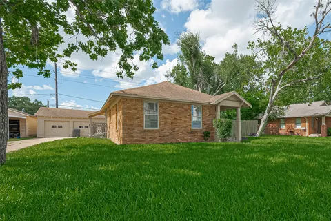 a front view of a house with a garden and trees