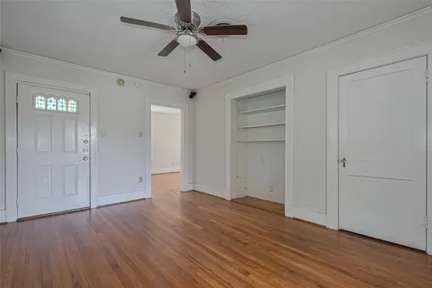 an empty room with wooden floor closet and ceiling fan