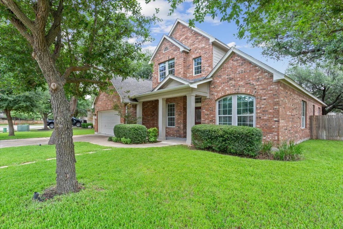 View of front of home with brick siding, an attached garage, and driveway