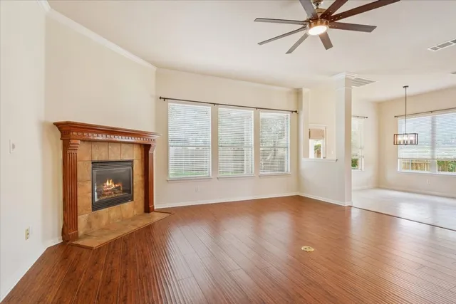 an empty room with wooden floor fan and windows
