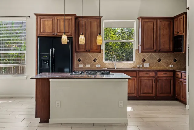 a kitchen with stainless steel appliances granite countertop a stove a sink and a refrigerator