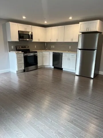 a kitchen with stainless steel appliances wooden floor and a refrigerator