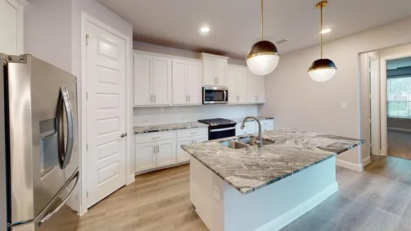 a kitchen with kitchen island granite countertop stainless steel appliances a stove refrigerator a sink a oven and a refrigerator with wooden floor