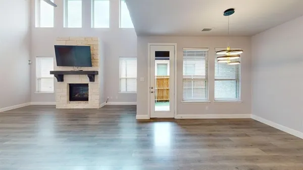 an empty room with wooden floor fireplace and windows