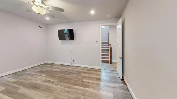 an empty room with wooden floor fan and windows