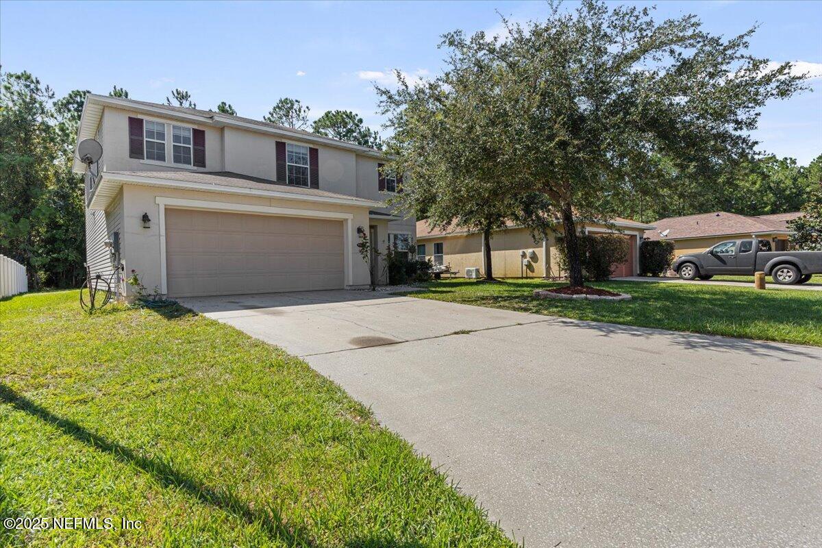 77347 Cobblestone Drive Yulee, FL 32097 - Photo 2 of 35 a front view of a house with a yard and garage