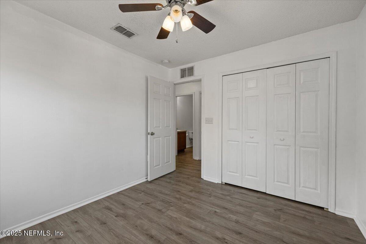 77347 Cobblestone Drive Yulee, FL 32097 - Photo 29 of 35 an empty room with wooden floor ceiling fan and windows